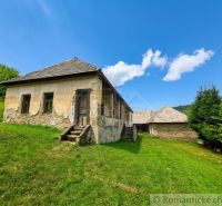 A family house in Dobroč with a historic facade, surrounded by a green meadow and a blue sky.