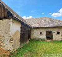 A family house in Dobroč with a stone facade, wooden cladding, and a shingle roof.