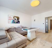 A bright living room with wood-patterned flooring and stylish furniture in a three-room apartment.