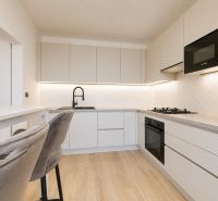 A kitchen in a 3-room apartment with white cabinets and a wood-patterned floor.