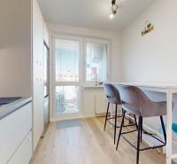A kitchen in a 3-room apartment with a wooden decor floor, a dining counter with chairs.