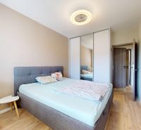 A bedroom with a bed, a wardrobe, and a wooden decor floor in a 3-room apartment.