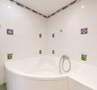 A bathroom with a corner bathtub and colorful tiles in a 3-room apartment.