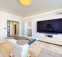 A living room in a 3-room apartment with a large TV and a floor with a wooden decor.