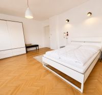 A bedroom with a large bed, a wardrobe, and a floor with a wooden decor in a 3-room apartment.
