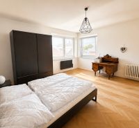 A bedroom in a 3-room apartment with a wooden decor floor and black furniture.