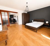 A bedroom in a 3-room apartment with a bed, wardrobe, and wooden decor flooring.