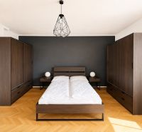 A bedroom in a 3-room apartment with dark furniture and a wooden decor floor.