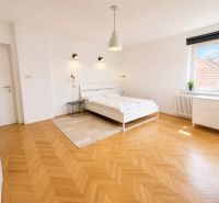 A bedroom in a 3-room apartment with white furniture and a wooden decor floor.
