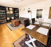 Living room in a three-room apartment with a wooden decor floor and a rich library.