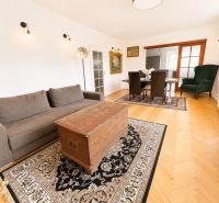 Living room with wood-patterned flooring, a comfortable couch, and a coffee table in a three-room apartment.