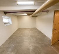A spacious cellar in a 3-room apartment with a concrete floor and ceiling lighting.