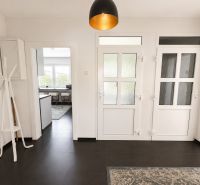 A hallway in a 3-room apartment with white doors and dark tiles on the floor.