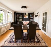 Living room with a bookshelf, wooden decor flooring, and a carpet in a three-room apartment.