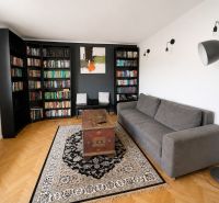 Living room with a bookshelf and a gray sofa in a 3-room apartment, floor with wood decor.