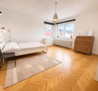 A bedroom in a 3-room apartment with a bed, a dresser, and a floor with a wooden decor.