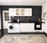 A kitchen in a 3-room apartment with white cabinets and a dark wall.
