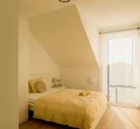 A bedroom in a family house with a wooden decor floor and soft beige tones.