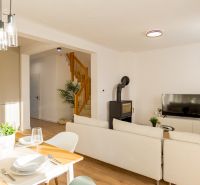 Dining room and living room with a fireplace and wood-patterned flooring in a family house.
