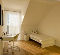 Bright children's room in a family house with a bed, desk, and wooden decor flooring.