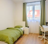 A room in a family house with a bed, a table, and a floor with a wooden decor.