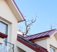 A part of the roof and balcony of a family house in Andovce with red details.