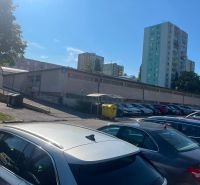 Parking lot near garages in Bratislava - Karlova Ves, Púpavová, surrounded by tall buildings.
