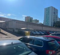 Garages on Púpavová Street in Bratislava - Karlova Ves with a parking lot and apartment buildings.