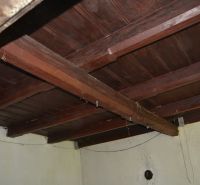 Wooden ceiling in the interior of a family house with rough plaster and electrical cables.