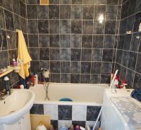 Bathroom in a 4-room apartment with dark tiles, a bathtub, and a sink.