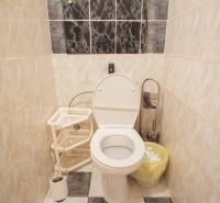 Bathroom in a 4-room apartment with a toilet, storage basket, and tiled wall.