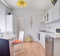 A kitchen in a 4-room apartment with white furniture, a table, and a wooden decor floor.