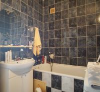 A bathroom with a shower curtain, bathtub, and black tiles in a 4-room apartment.