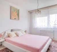 A bedroom in a 4-room apartment with white walls, a decorative carpet, and a bed.