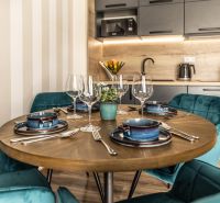 Dining table with placemats and glasses in a 2-room apartment, floor with wood decor.