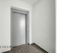 A hallway in a 2-room apartment with a gray elevator and tiles on the floor.