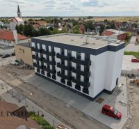 Zlaté Klasy: A view of a new building with 2-bedroom apartments and surrounding family houses.
