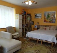 Bedroom in a family house with a large window, sofa, and wall paintings.