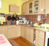 A kitchen in a family house with beige cabinets and a wood-patterned floor.