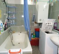 A bathroom in a family house with a bathtub, sink, and washing machine.