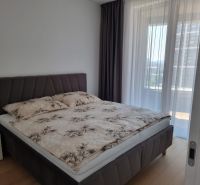 Bedroom in a 2-room apartment with a bed and a window with thin curtains.