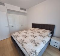 Bedroom in a two-room apartment with a double bed and a built-in wardrobe, wooden decor flooring.