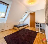 A bright room with dormer windows, a bed, and a table in a 5 or more room apartment.