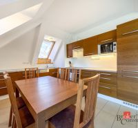 A kitchen in a 5 or more room apartment with a wooden decor floor and an attic window.