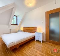 A bedroom with a wood-patterned floor in a five or more room apartment.