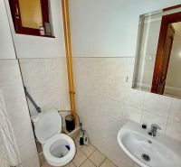 Bathroom in offices with a toilet, sink, and window.