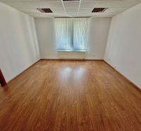 Living office with wood-patterned flooring and windows with vertical blinds.