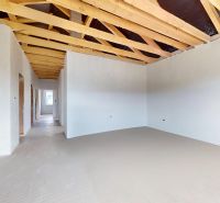 Interior of a family house with an exposed wooden ceiling and light-colored walls.