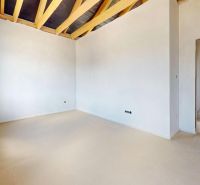 A spacious room in a family house with a wooden decor floor and exposed beams.
