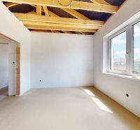 Interior of a family house with white walls, a large window, and exposed wooden beams.